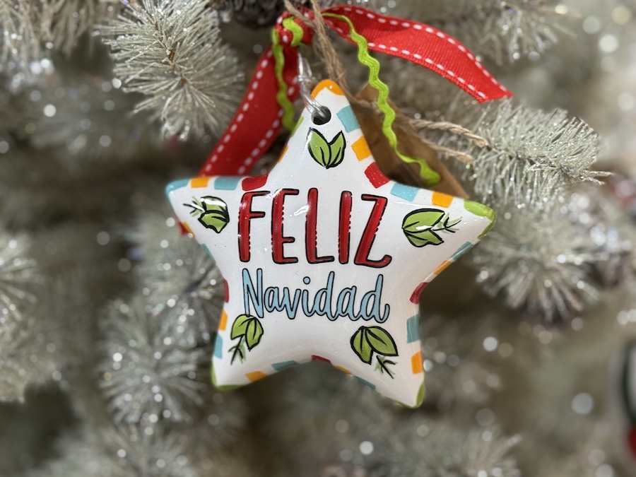 Star-shaped “Feliz Navidad” ornament hanging on a decorated tree