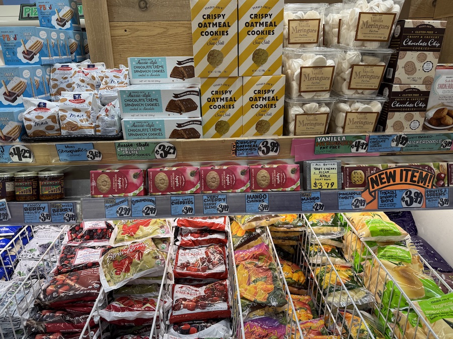 A shelf full of Trader Joe’s cookies in holiday packaging, offering buttery shortbread, crunchy oatmeal, and chocolate creme sandwiches.