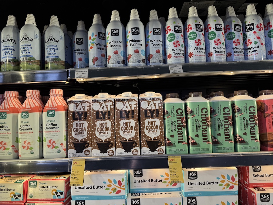 A cozy beverage display featuring hot cocoa mix, oatmilk, creamers, and whipped toppings for holiday drinks.