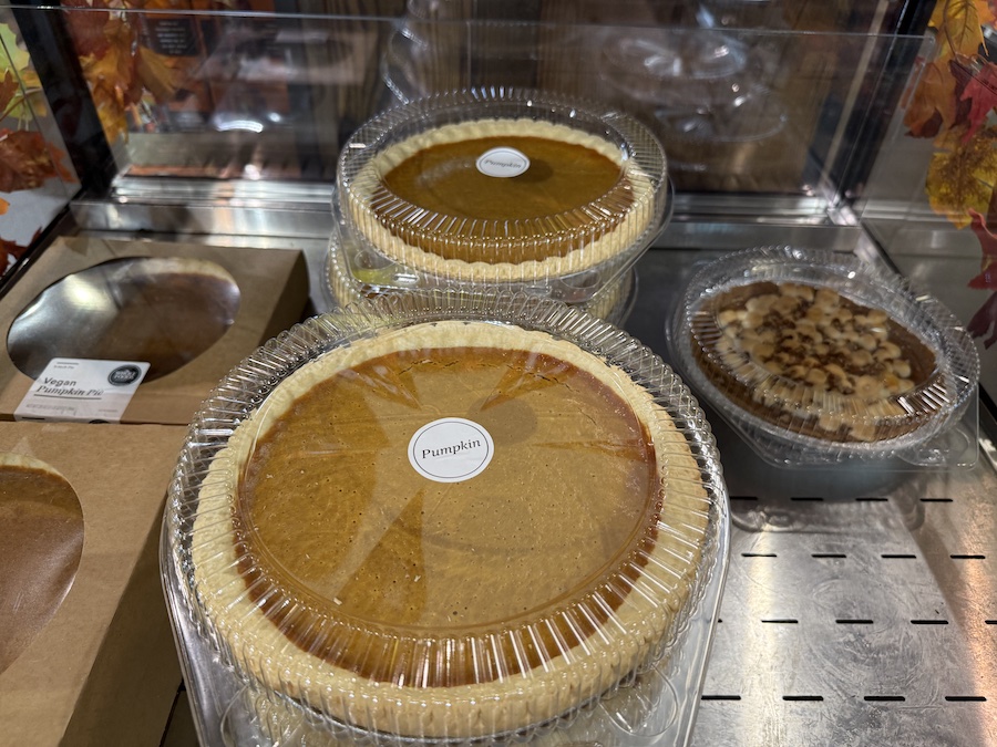Freshly baked pumpkin pies in clear containers displayed in the Whole Foods bakery section.