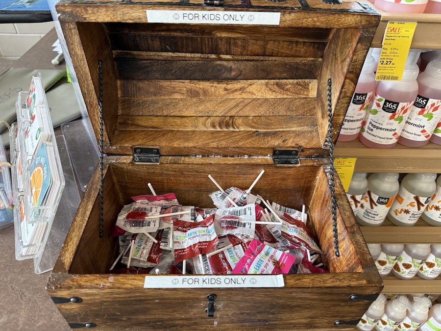 Small wooden treasure chest labeled “For Kids Only,” filled with YumEarth organic lollipops in colorful wrappers.