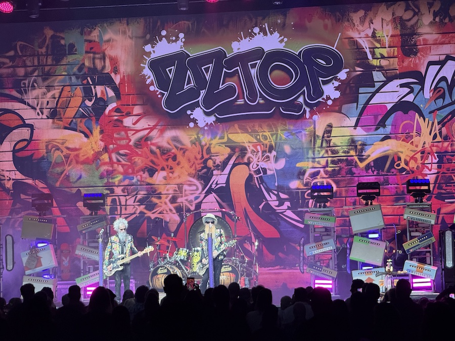 ZZ Top performing under vibrant stage lights, guitars in sync as the crowd cheers.