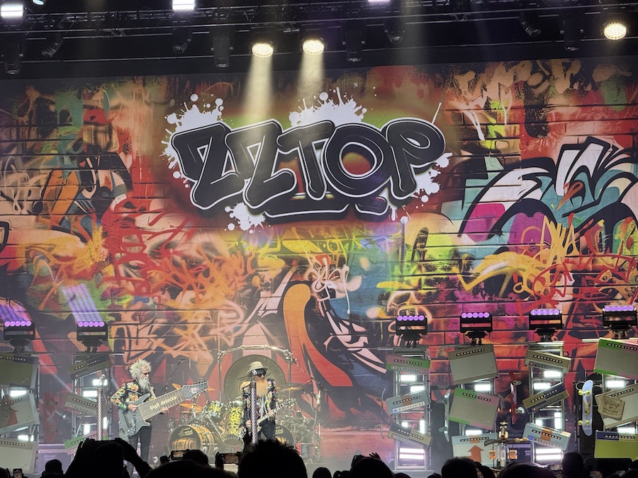 The trio silhouetted against bright backlights, creating a dramatic concert moment.