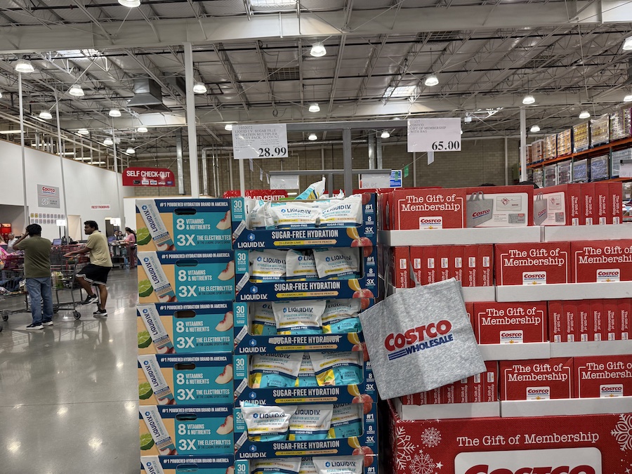 A wide shelving display inside Costco featuring neatly stacked “The Gift of Membership” gift bags.