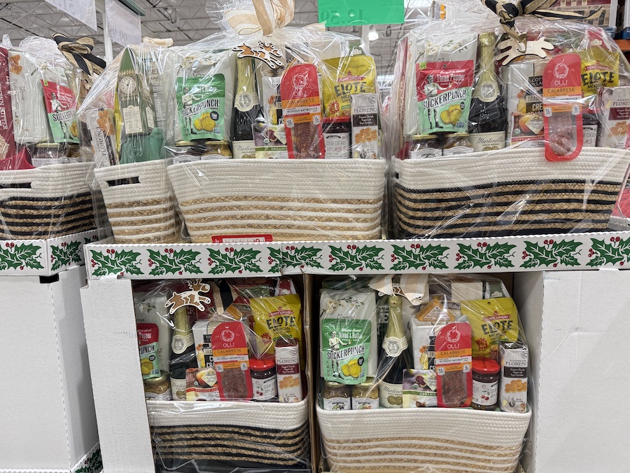 A large woven basket filled with gourmet treats, wrapped in clear cellophane with a festive bow.