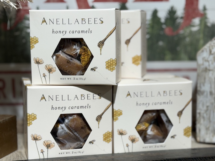 Packages of Anellabees honey caramels displayed on a wooden shelf, offering artisan holiday treats.