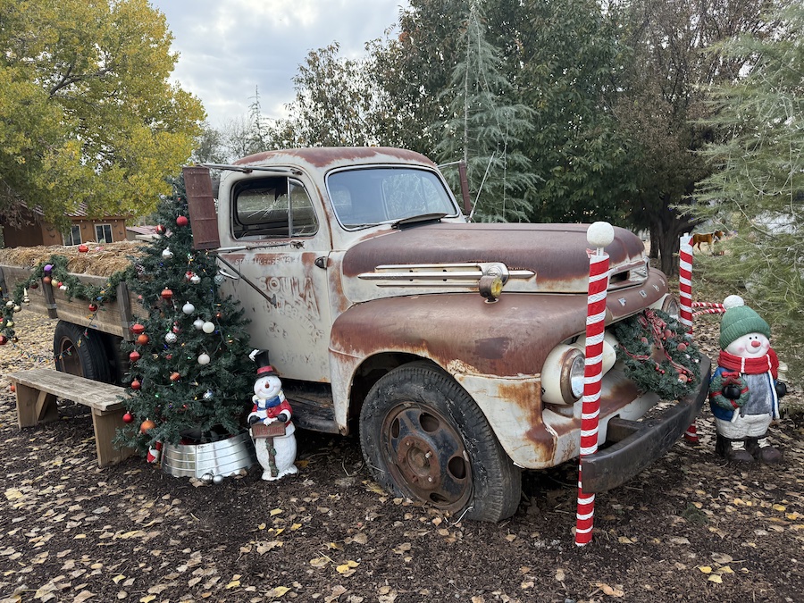A classic red Ford truck beautifully decorated with wreaths, lights, and festive greenery for the Christmas season.