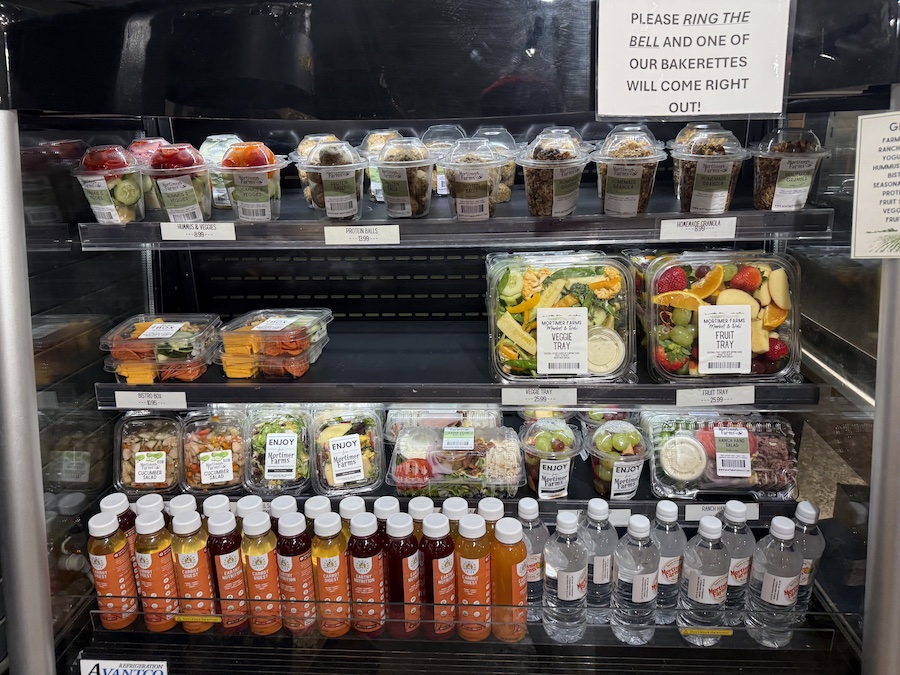 Clear containers filled with fresh, colorful vegetable salads sourced from the farm’s produce.