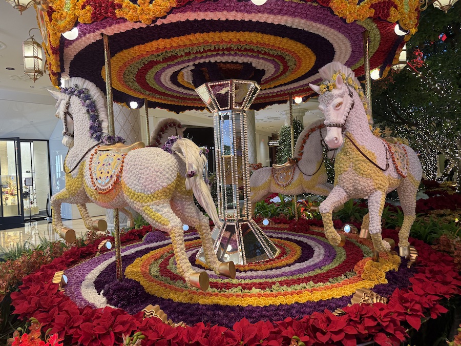 The full carousel display surrounded by holiday décor, showcasing Wynn’s signature colorful, artistic style.