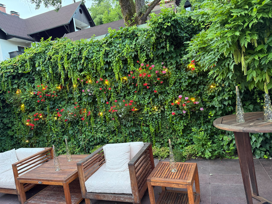 Outdoor lounge seating beside a flower-covered green wall at Kendov Dvorec