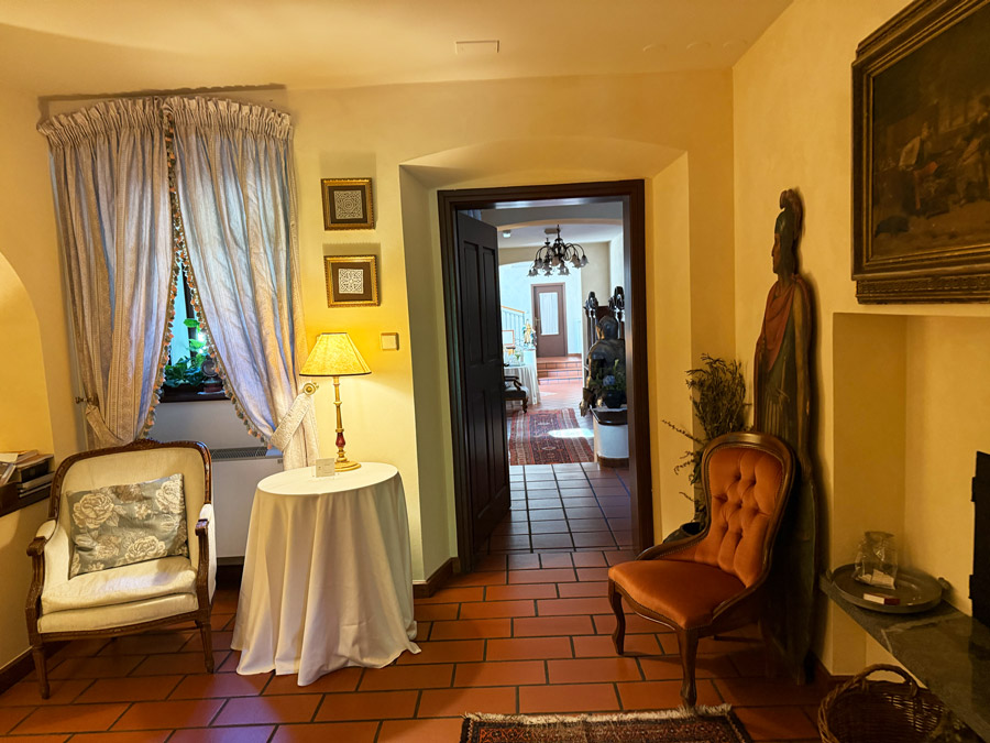 Historic interior at Kendov Dvorec with antique chairs, traditional artwork, warm lighting, and terracotta floors