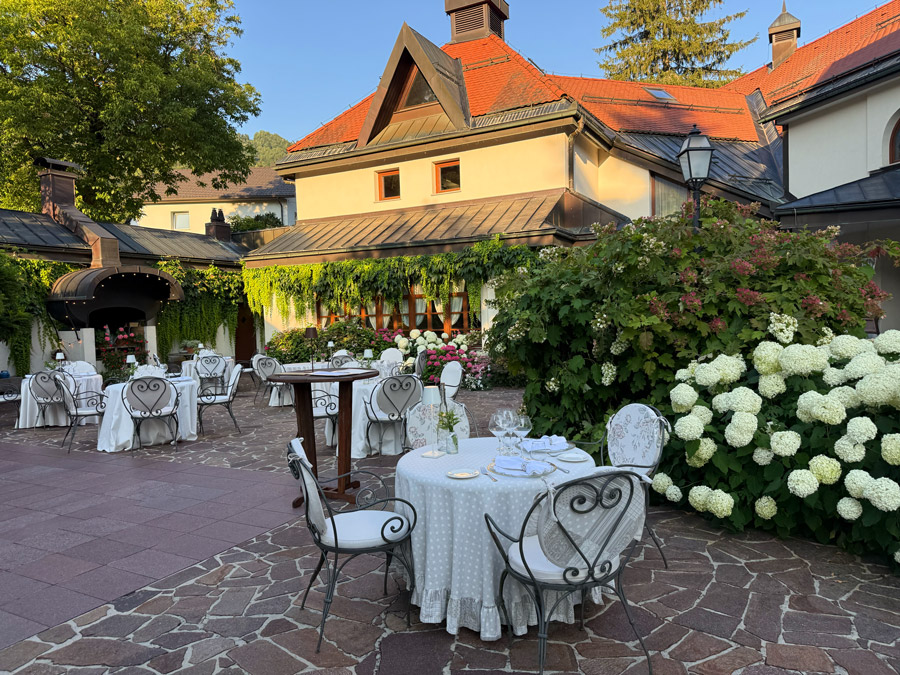 Outdoor restaurant courtyard at Kendov Dvorec surrounded by hydrangeas and historic buildings