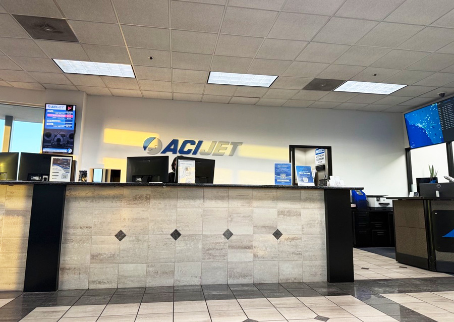 Reception desk beneath the ACI Jet logo inside the FBO terminal