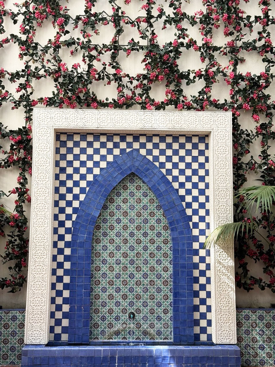 Blue-and-white tiled decorative fountain framed by flowering vines at Kimpton Canary Hotel