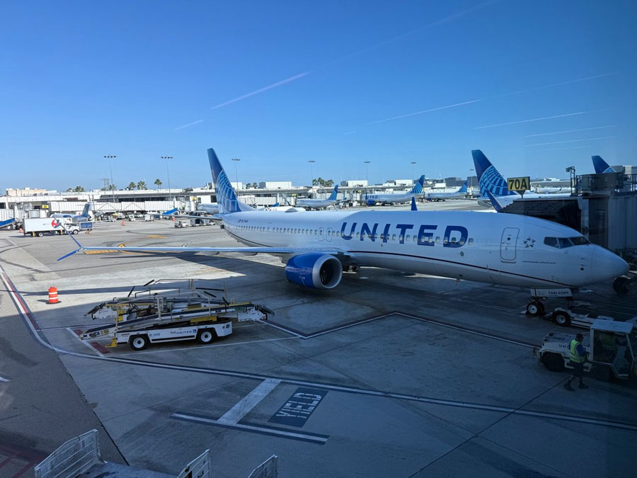United aircraft parked at LAX Gate 70A, with ground service vehicles beside it.